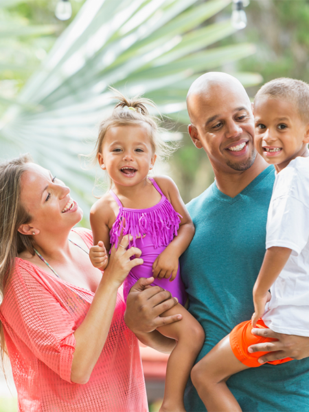 Family of mother, father, son and daughter laughing in tropical environment