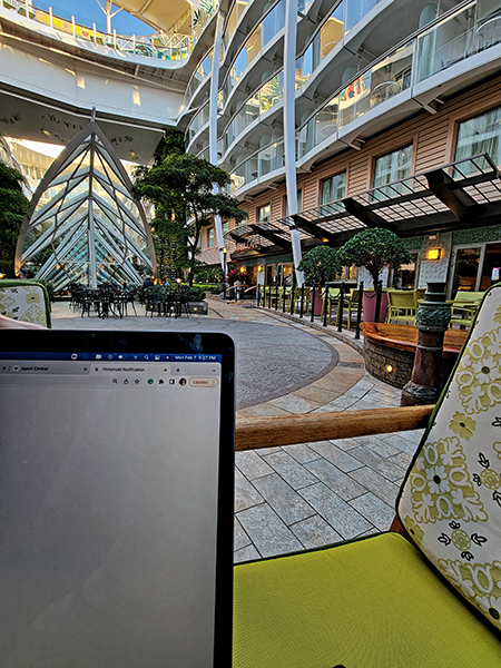 photo on board a Royal Caribbean Cruise ship, from the perspective of someone working on a laptop. Shows a courtyard and open roof, modern design